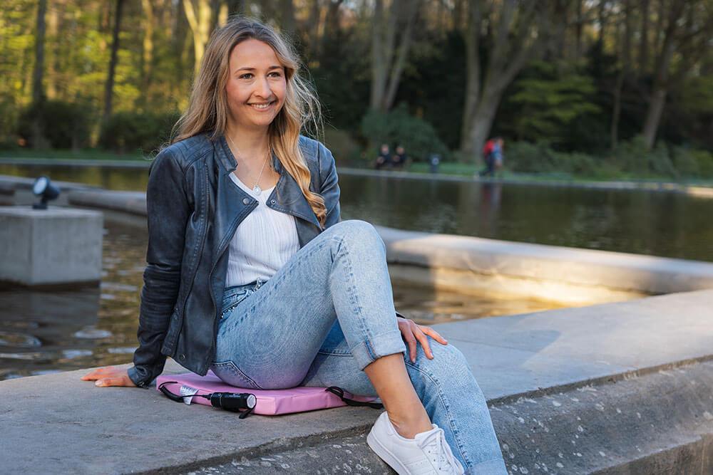 Frau sitzt im Park mit Ihrer mobilen Sitzheizung